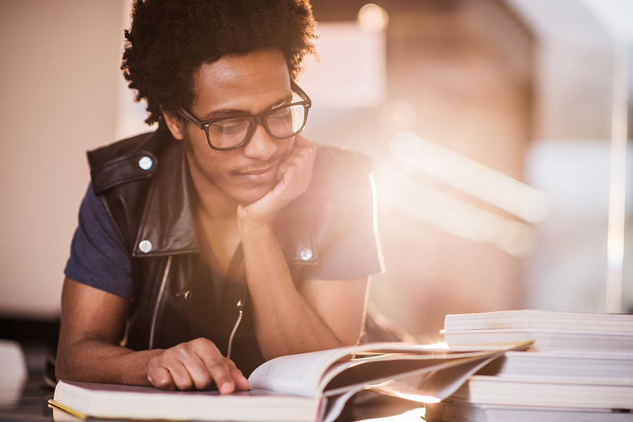 Smiling African American young man studying. Photograph by Skynesher