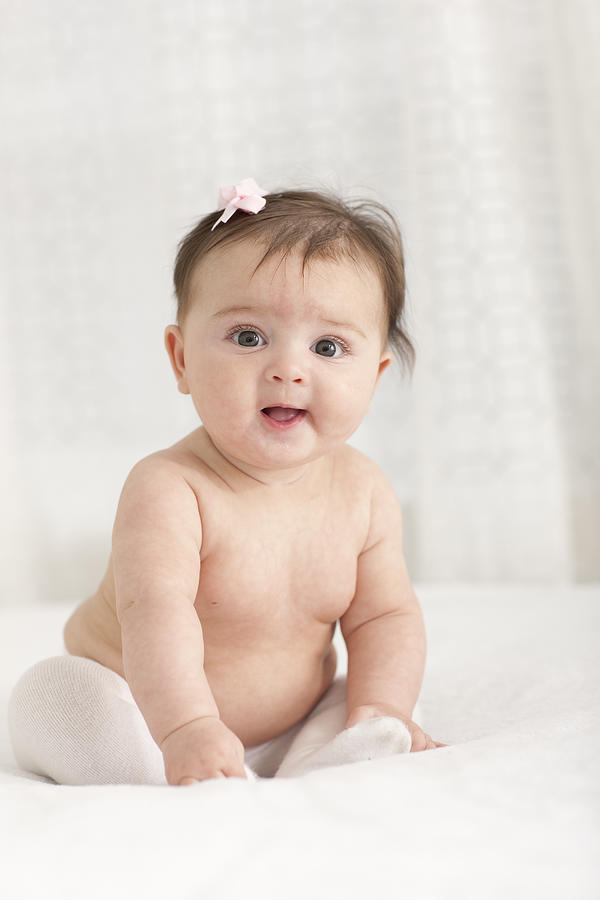 Smiling baby girl with bow in hair. Photograph by Marcy Maloy