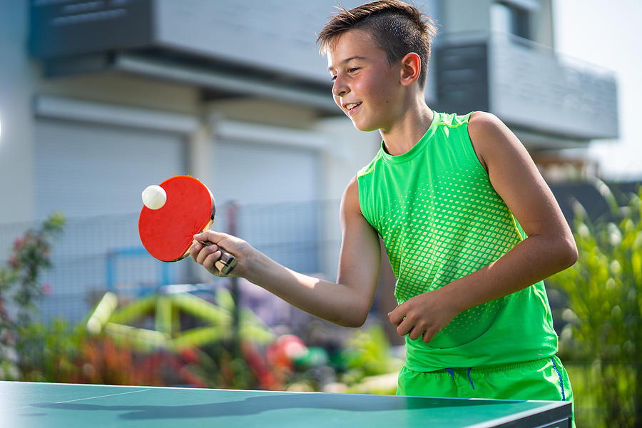 Smiling Boy Playing Table Tennis In Garden Photograph by Amriphoto