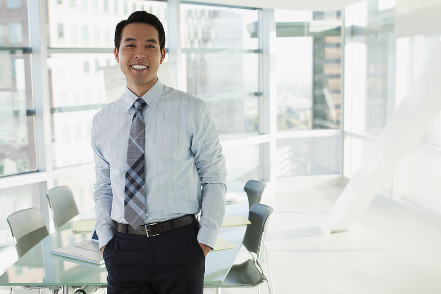 Smiling businessman standing in office Photograph by Sam Edwards