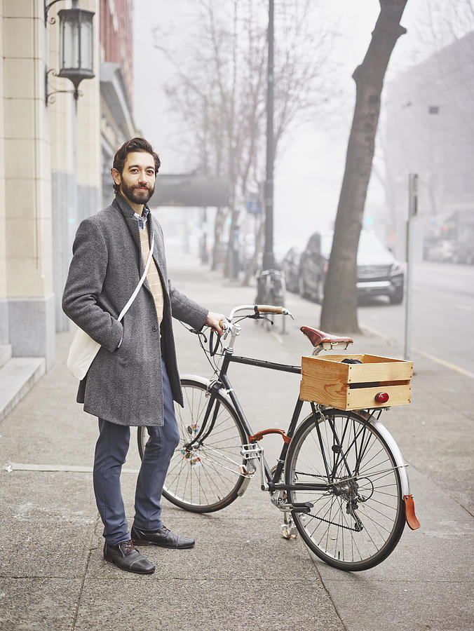 Smiling businessman standing next to bike Photograph by Thomas Barwick