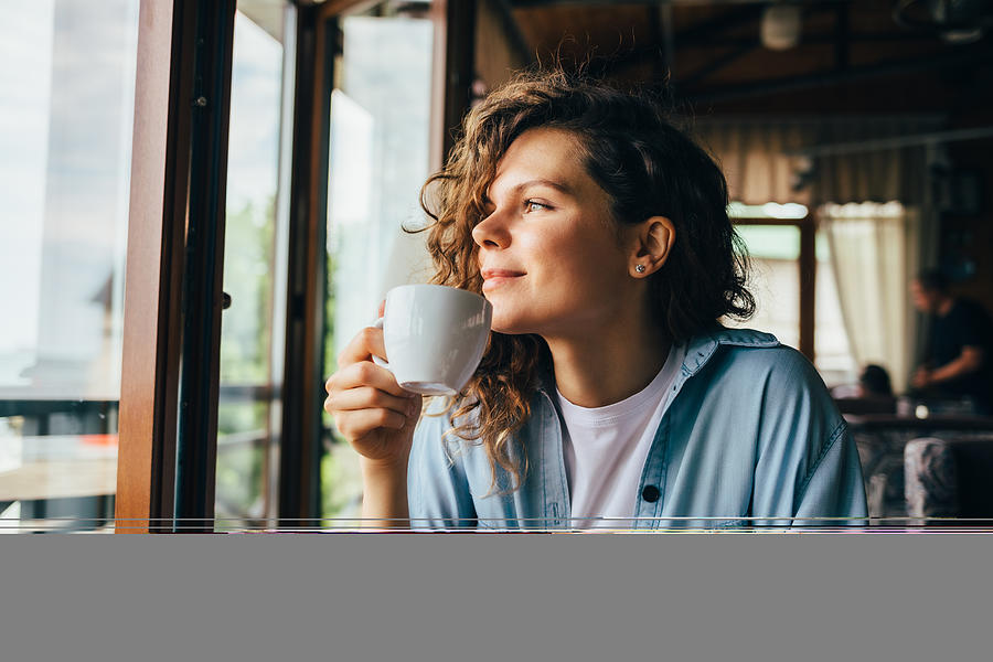 Smiling calm young woman drinking coffee Photograph by Iprogressman