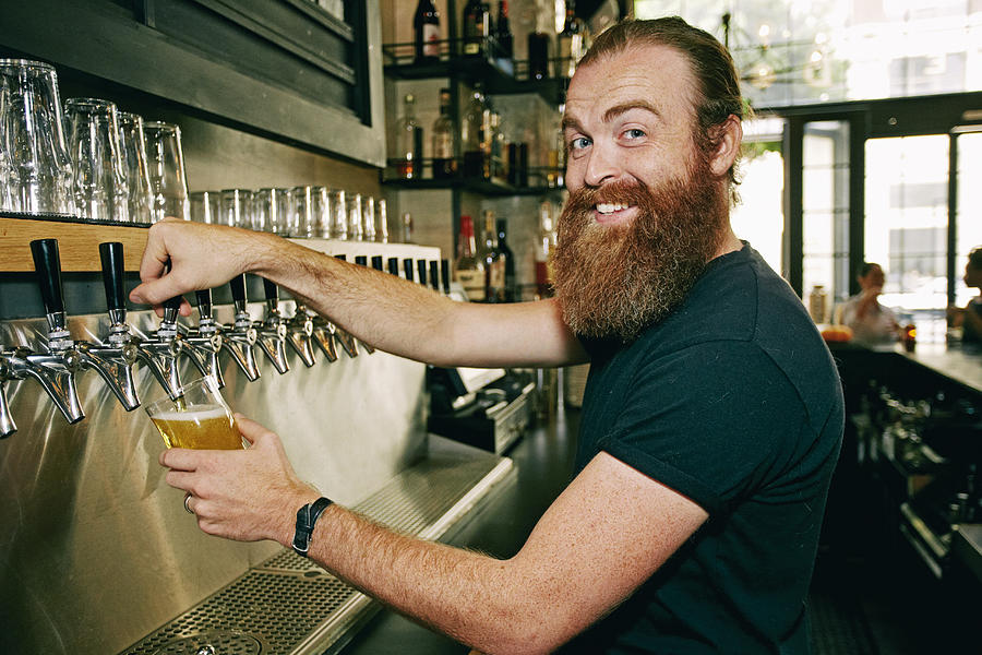 Smiling Caucasian bartender pouring beer Photograph by Peathegee Inc