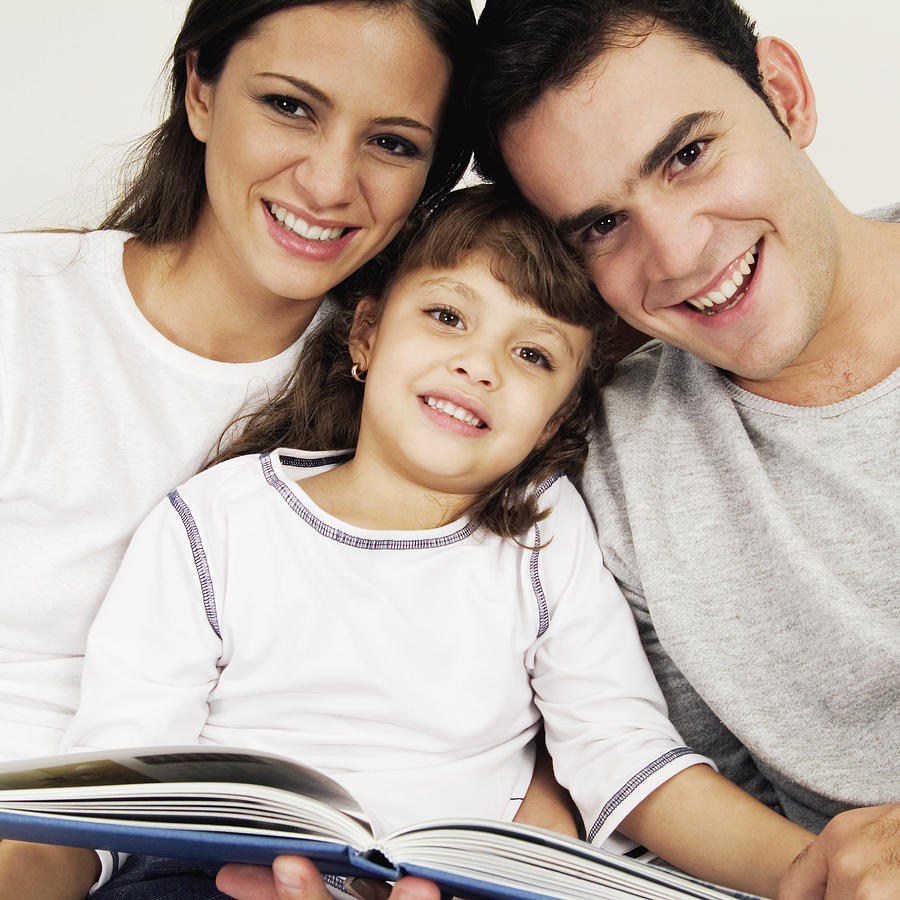 Smiling couple and child with scrapbook, close-up Photograph by Medioimages/Photodisc