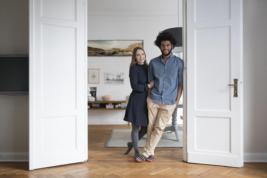 Smiling couple at home standing in door frame Photograph by Westend61
