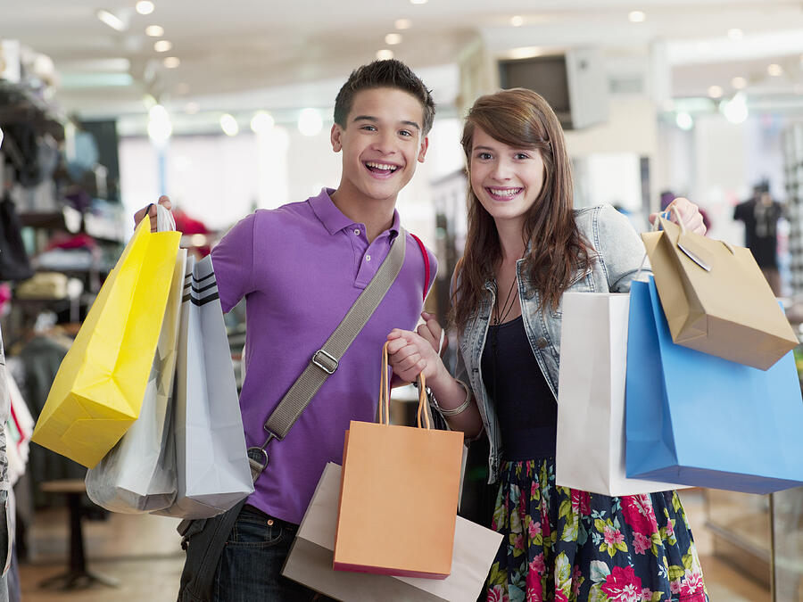 Smiling couple carrying shopping bags in store Photograph by Chris Ryan