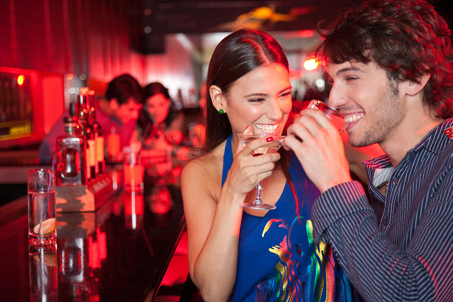 Smiling couple in nightclub with beverage Photograph by Paul Bradbury