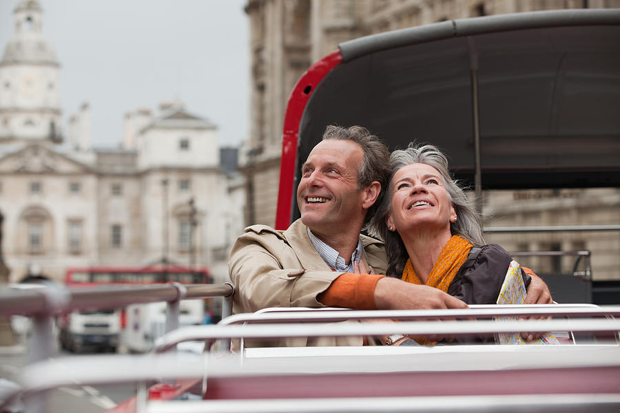 Smiling couple looking up on double decker bus in London Photograph by Sam Edwards