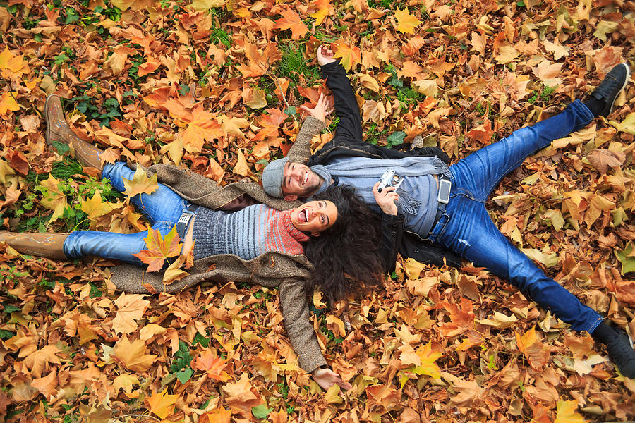 Smiling couple lying down on leaves carpet Photograph by Valentinrussanov