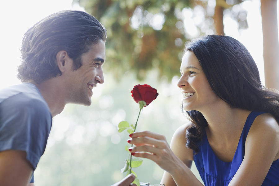 Smiling couple outdoors with red rose Photograph by Tom Merton