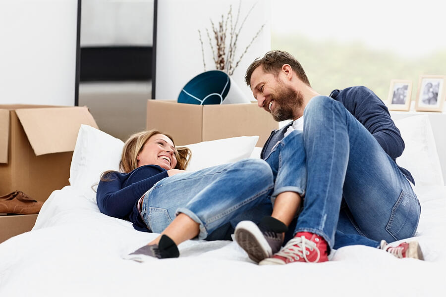Smiling couple relaxing by boxes in their new house Photograph by Dmp