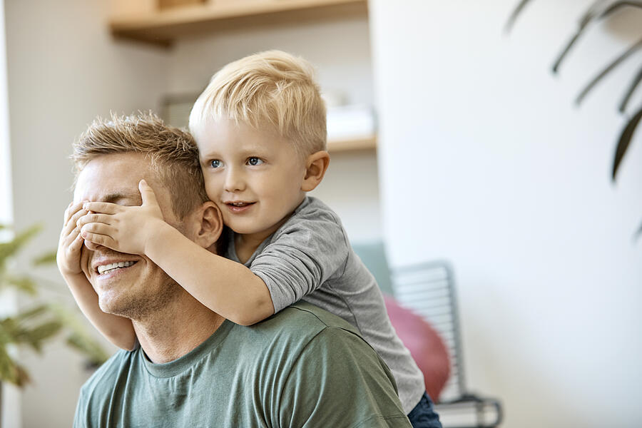 Smiling cute blond boy covering eyes of father Photograph by Nomad