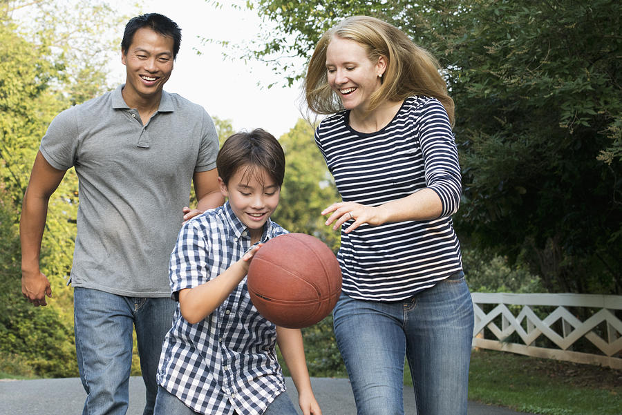 Smiling family playing basketball Photograph by Ariel Skelley