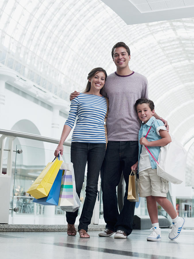 Smiling family shopping together in mall Photograph by Chris Ryan