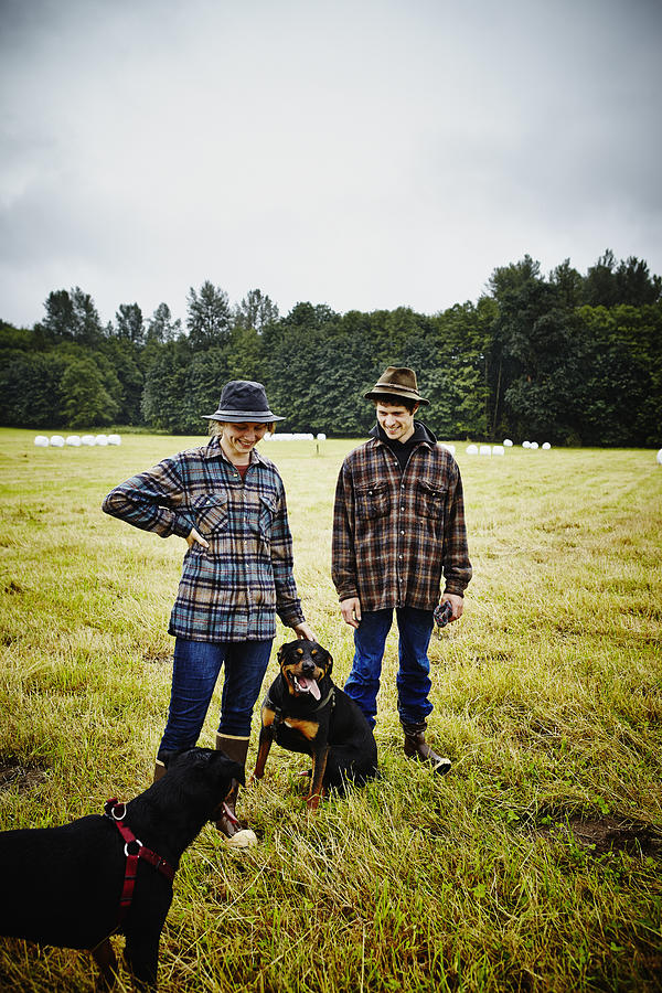 Smiling farmer couple in pasture with two dogs Photograph by Thomas Barwick