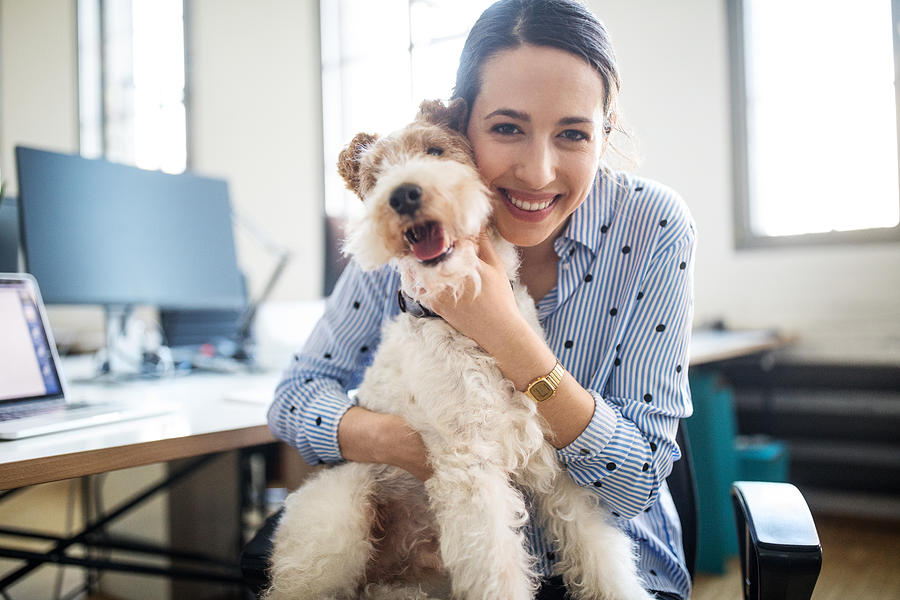 Smiling female entrepreneur sitting with dog Photograph by Luis Alvarez