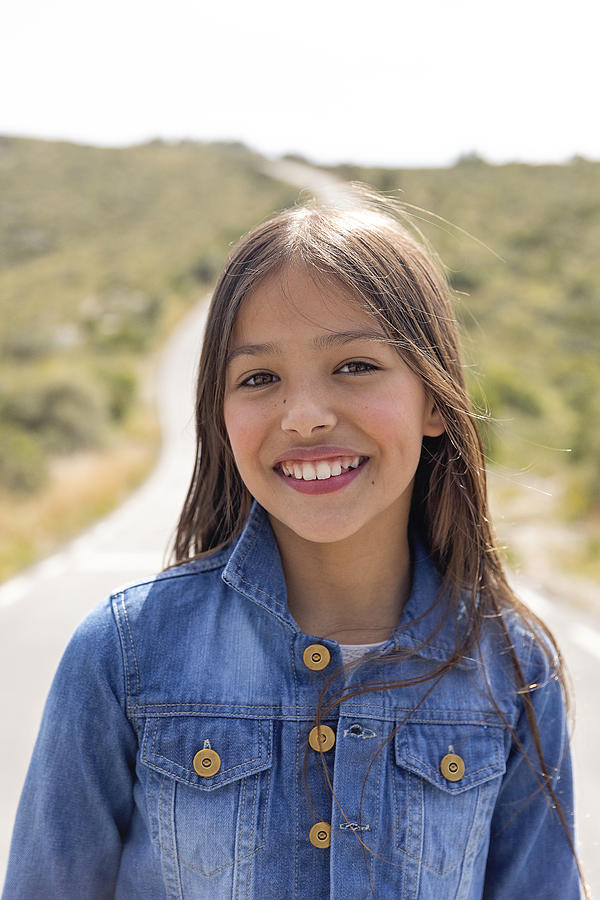 Smiling girl in denim jacket on road Photograph by Westend61