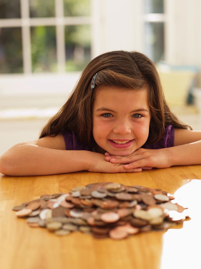 Smiling girl looking at pile of coins Photograph by Chris Ryan