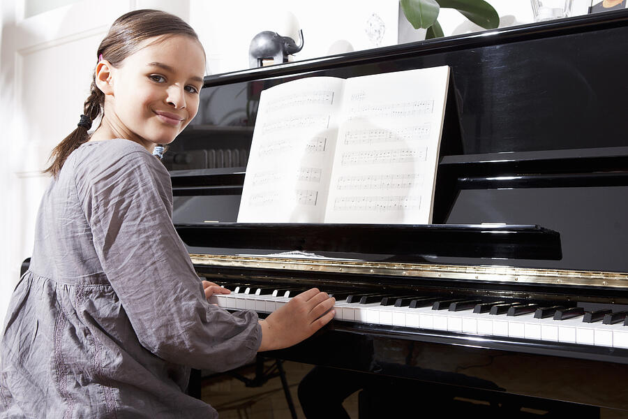 Smiling girl practicing at piano Photograph by Severin Schweiger