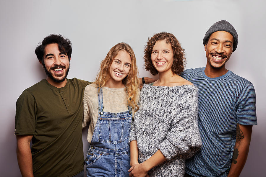 Smiling group of diverse young friends against a gray background Photograph by Goodboy Picture Company