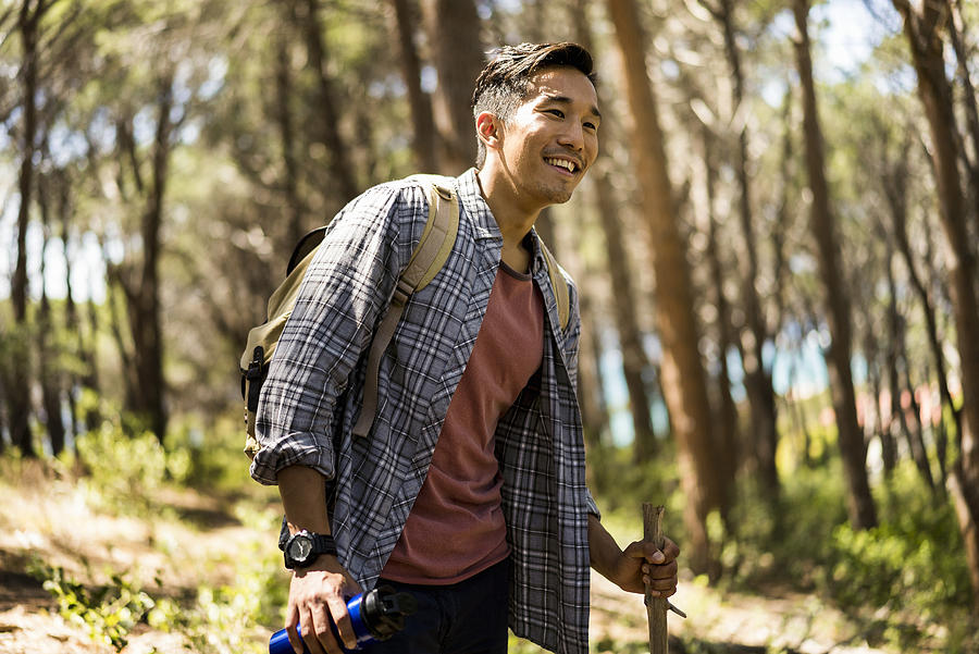 Smiling hiker holding stick and water bottle Photograph by Portra