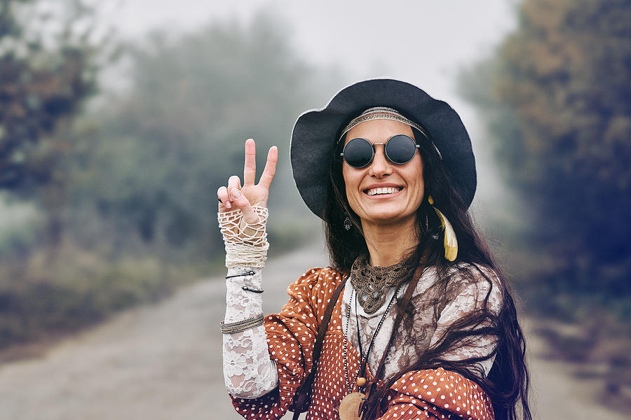 Smiling hippie woman giving peace sign Photograph by YorVen
