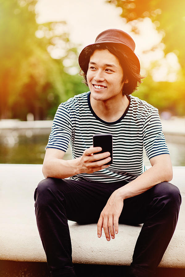 Smiling japanese teenager with smart phone Photograph by Pixelfit