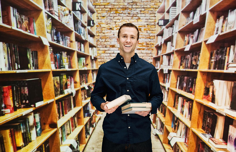 Smiling male bookseller in library Photograph by 4x6