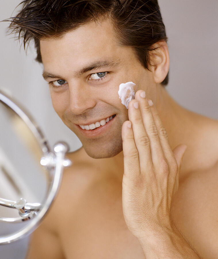 Smiling Man Applying Moisturizer to His Face Photograph by Flying Colours Ltd