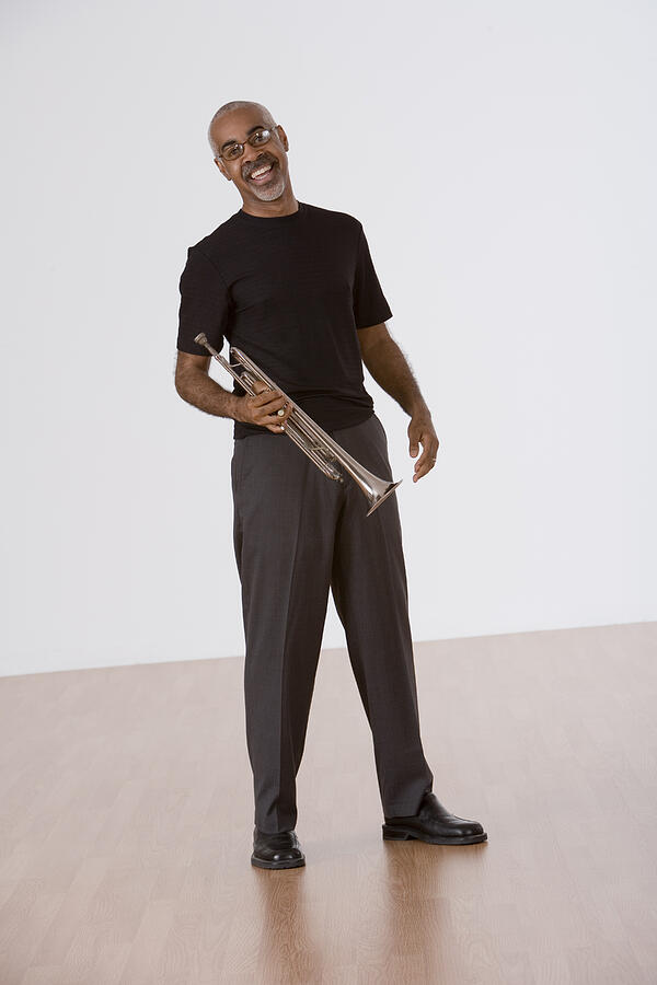 Smiling man holding trumpet Photograph by Comstock Images