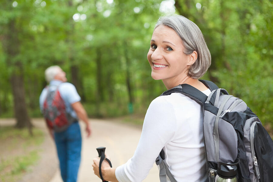 Smiling mature woman hiking on trail with husband Photograph by SDI Productions