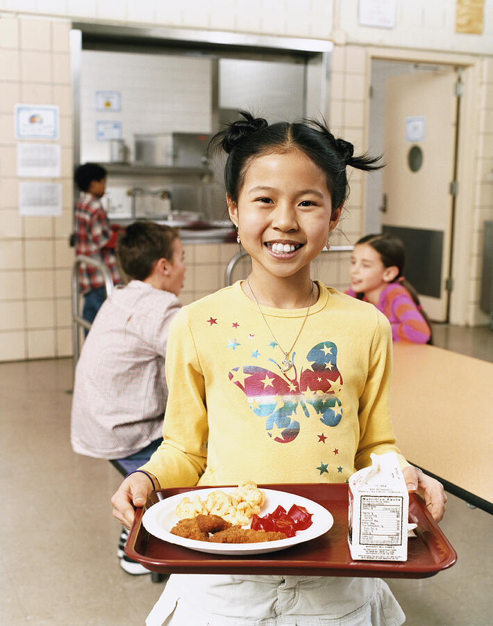 Smiling Schoolgirl Carrying a Tray With Food Photograph by Digital Vision.