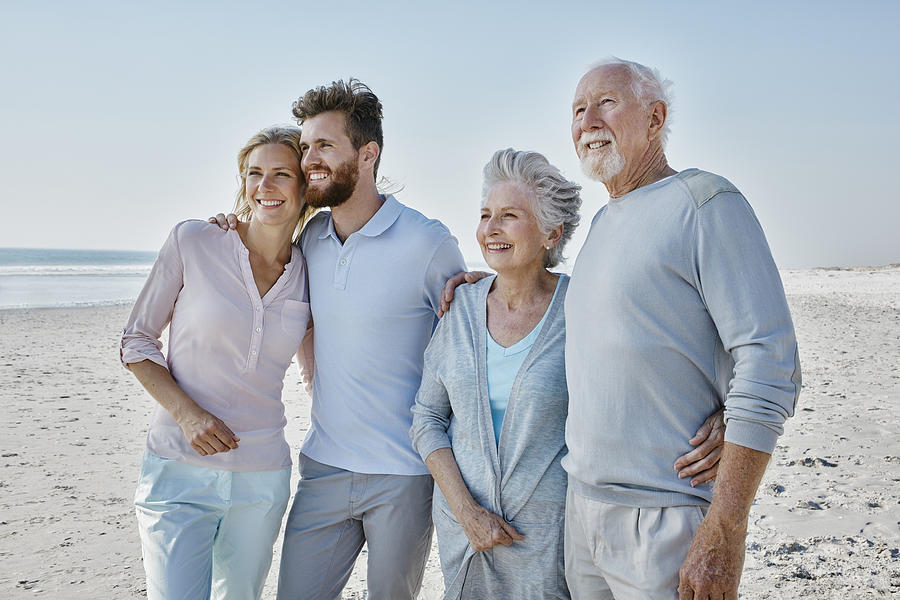 Smiling senior couple with adult children on the beach Photograph by Westend61