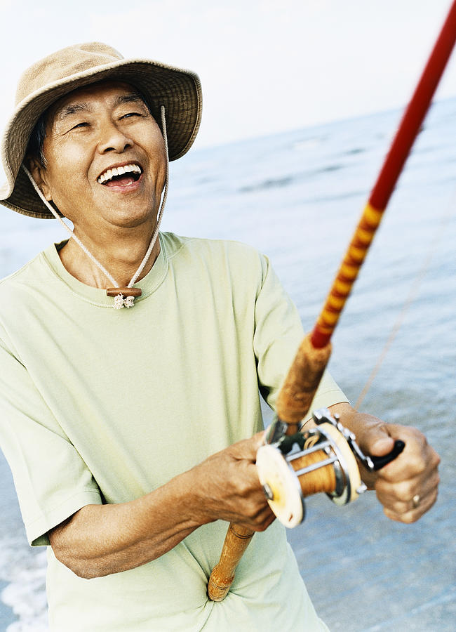 Smiling Senior Man Holding a Fishing Rod Photograph by Digital Vision.