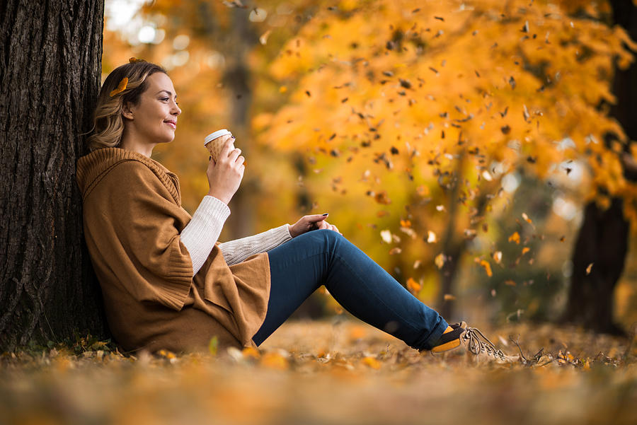 Smiling woman enjoying in coffee at the park. Photograph by BraunS