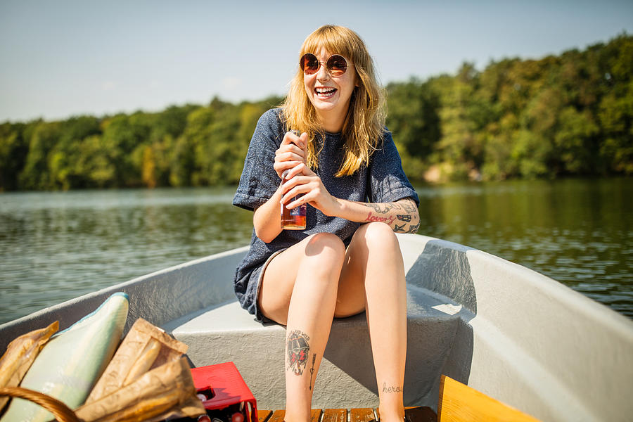 Smiling woman holding beer on rowboat Photograph by Luis Alvarez
