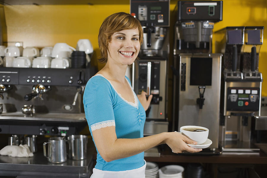 Smiling woman holding cup of coffee Photograph by Jupiterimages