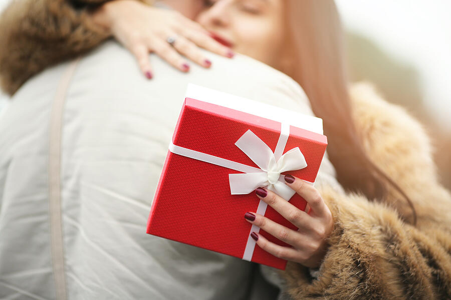 Smiling woman holding valentines day gift and hugging man Photograph by Handemandaci