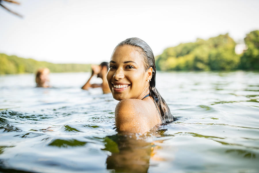 Smiling woman in a lake with friends Photograph by Luis Alvarez