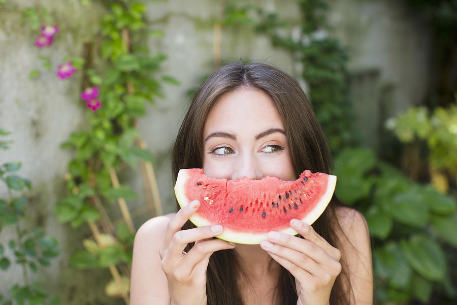 Smiling woman playing with watermelon Photograph by Lilly Bloom