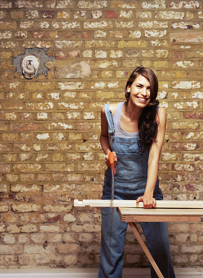 Smiling woman sawing wood Photograph by Image Source