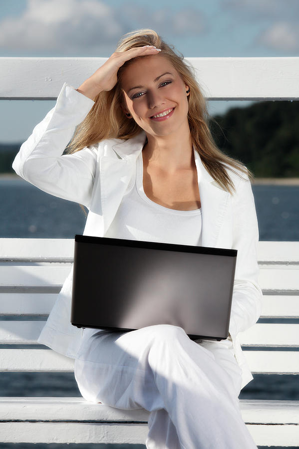 Smiling woman using laptop outdoors Photograph by Fotek