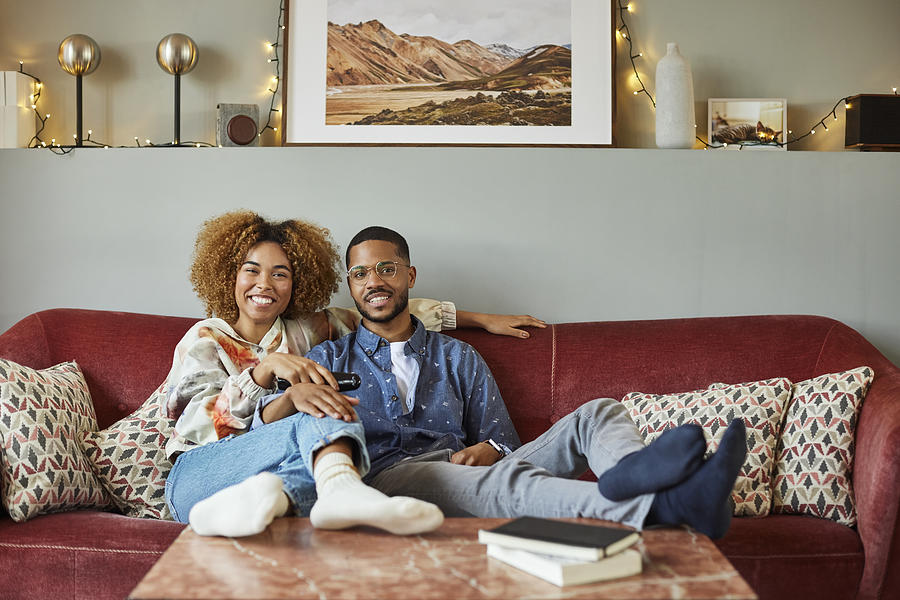 Smiling Woman With Boyfriend Watching TV At Home Photograph by Morsa Images