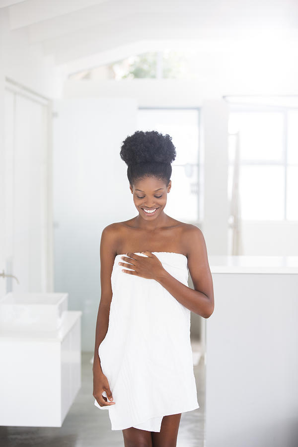 Smiling woman wrapped in towel in bathroom Photograph by David Lees