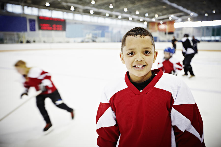 Smiling young hockey player standing on ice Photograph by Thomas Barwick