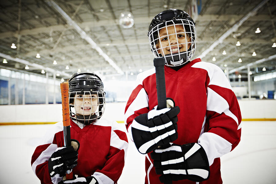 Smiling young hockey players standing on ice Photograph by Thomas Barwick