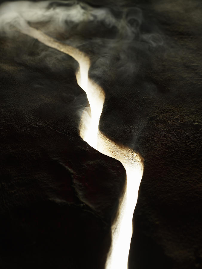 Smoke and light coming through crack in lava rock, elevated view Photograph by Ryan McVay