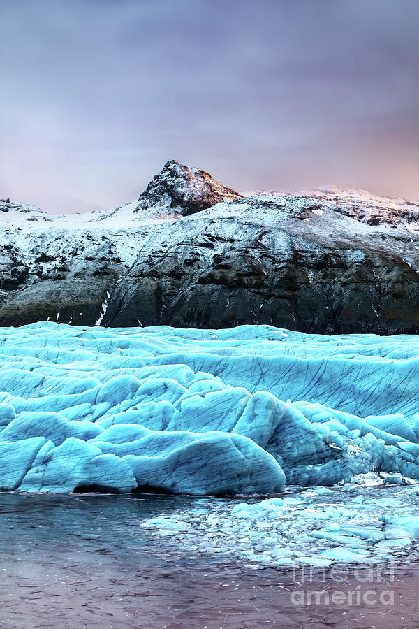 Snow covered mountain and blue glacial ice of the Svinafellsjokul glacier in southeast Iceland. This is the largest ice cap in Europe. Winter scene at dusk. Photograph by Jane Rix