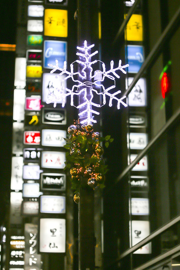 Snowflake shaped Christmas lights against sign boards and neon on Konbaru Dori Street in Ginza Photograph by DigiPub