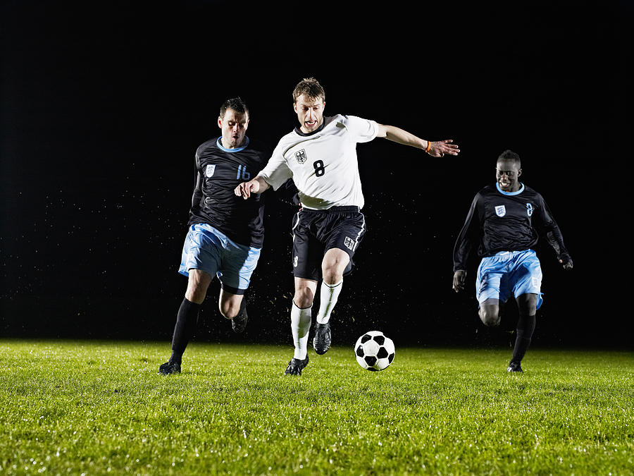 Soccer player dribbling ball past opposing team Photograph by Thomas Barwick